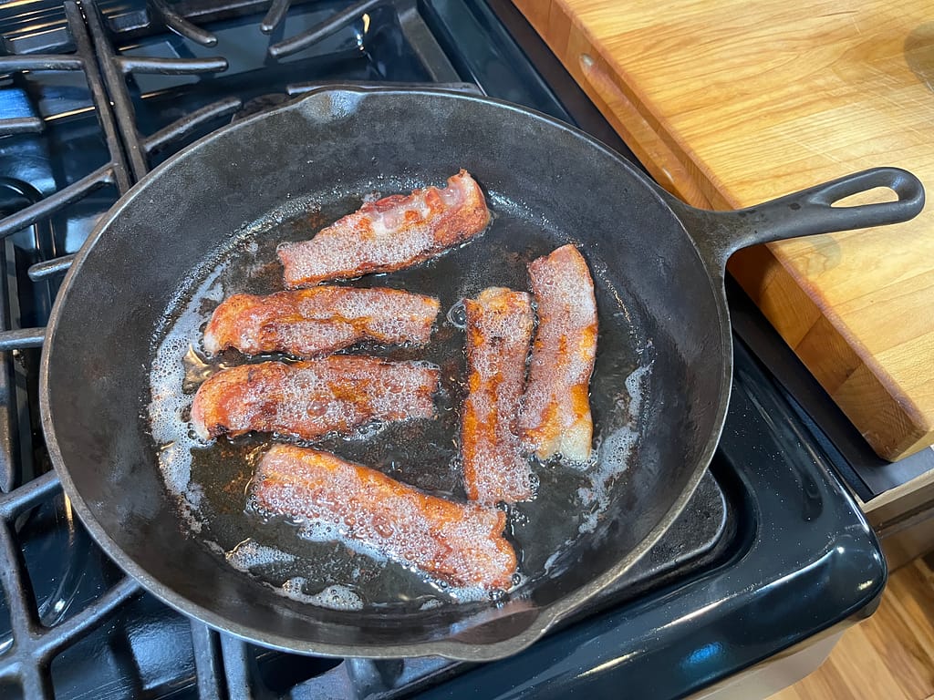 bacon cooking in cast iron skillet