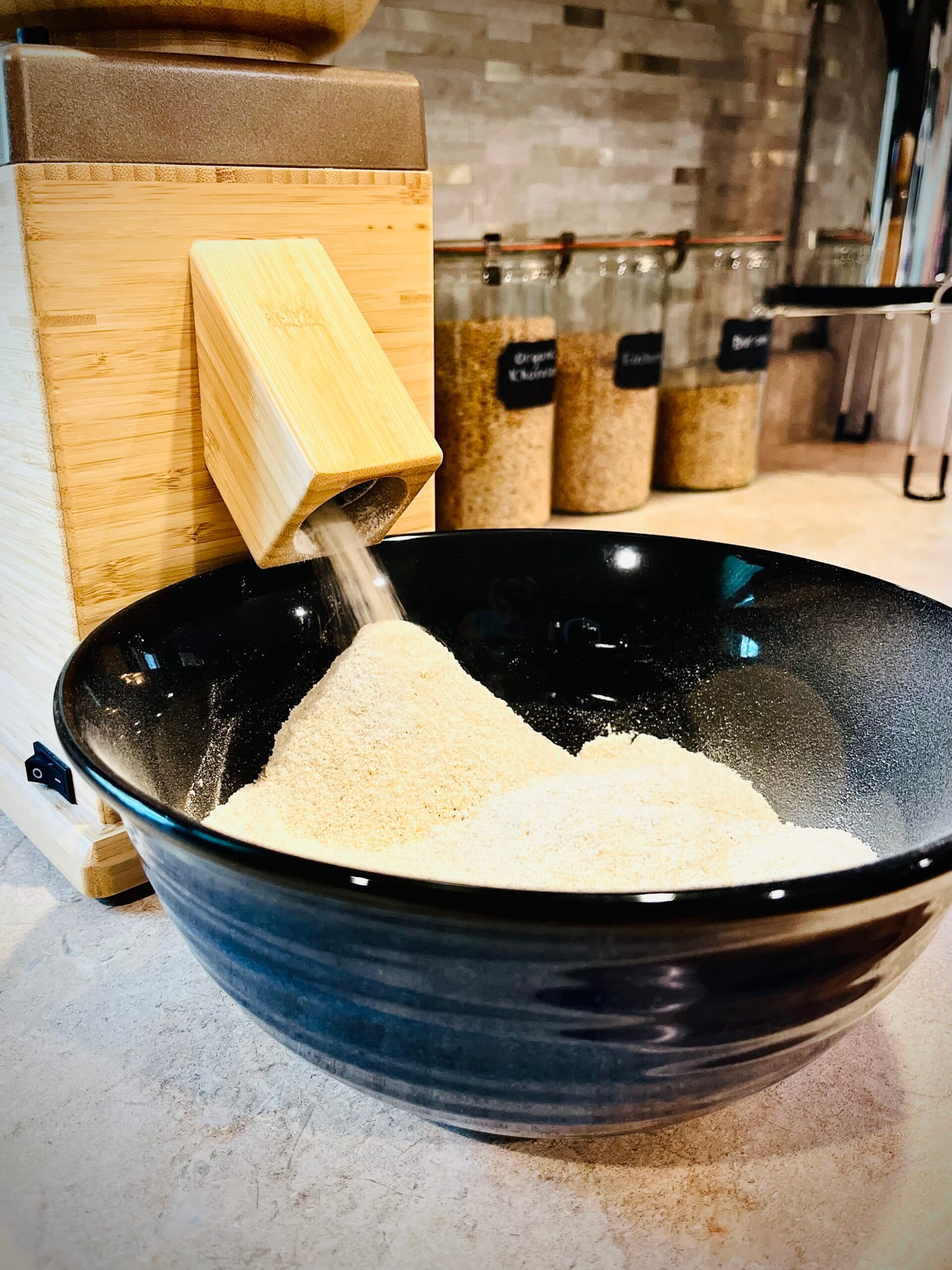 NutriMill Harvest milling fresh flour into blue bowl.