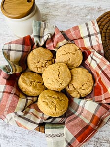 Biscuits made with fresh milled flour in plaid towel next to honey pot.