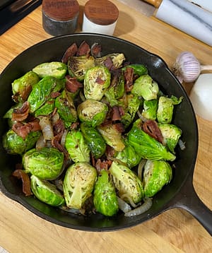 savory brussels sprouts in cast iron pan with bacon, onions, and garlic