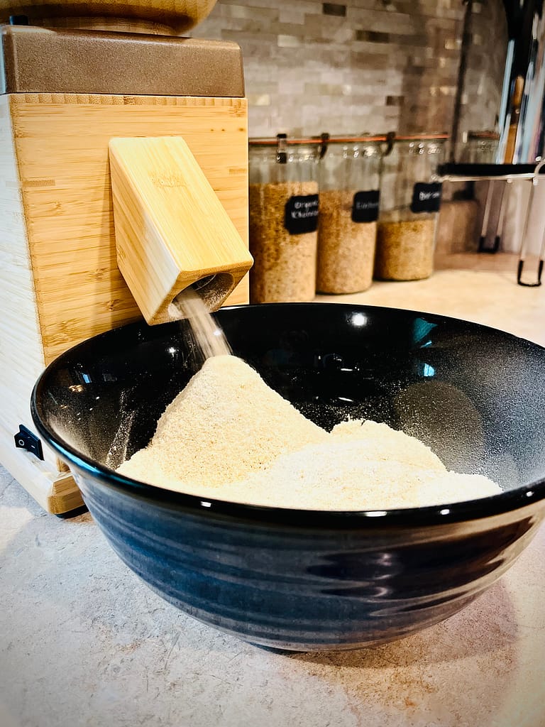 NutriMill Harvest milling fresh flour into blue bowl.